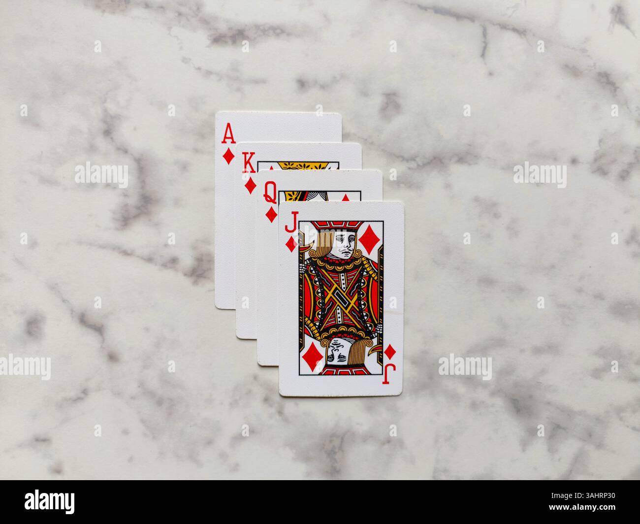 flat-lay photograph showcases perfect royal flush in diamonds Ace, King, Queen, Jack, neatly stacked and centered on a polished white marble surface - Smartphone Captured Stock Image