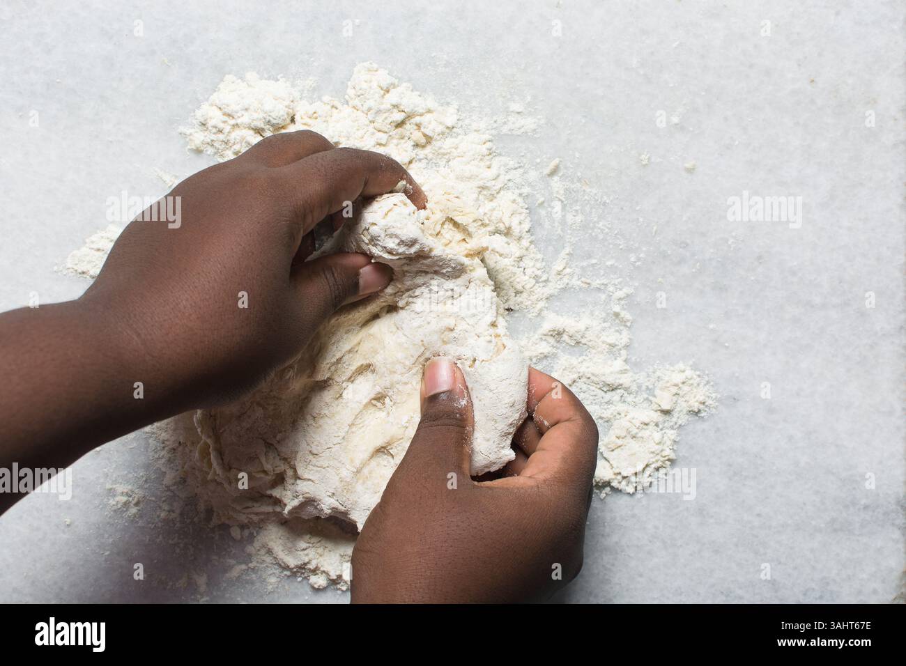 Overhead view of baozi dough being kneaded on a white countertop, top ...