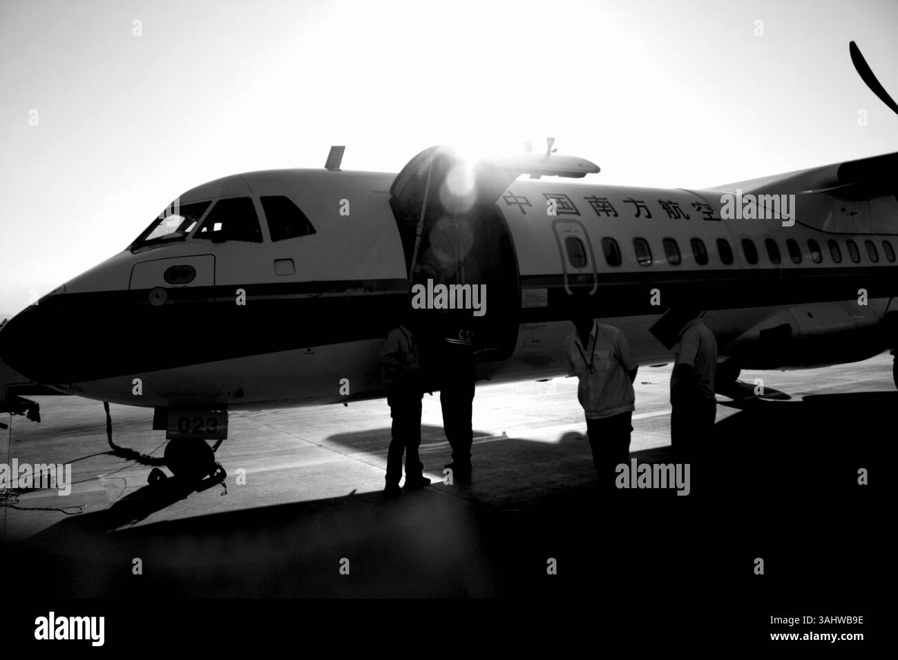 Sunset silhouette of a China Southern Airlines ATR72 ( French aerospace company Aerospatiale ) aircraft with ground crew at airport gate, aviation and travel industry, aircraft maintenance, aircraft operations, aviation photography. 2008. Stock Photo