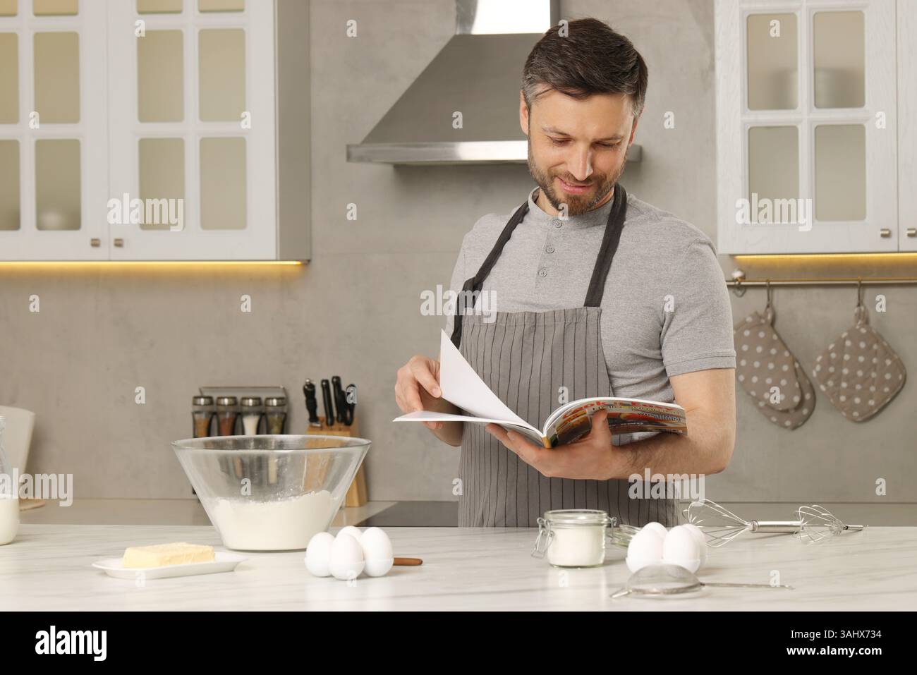Happy man reading recipe in culinary magazine while cooking at home Stock Photo