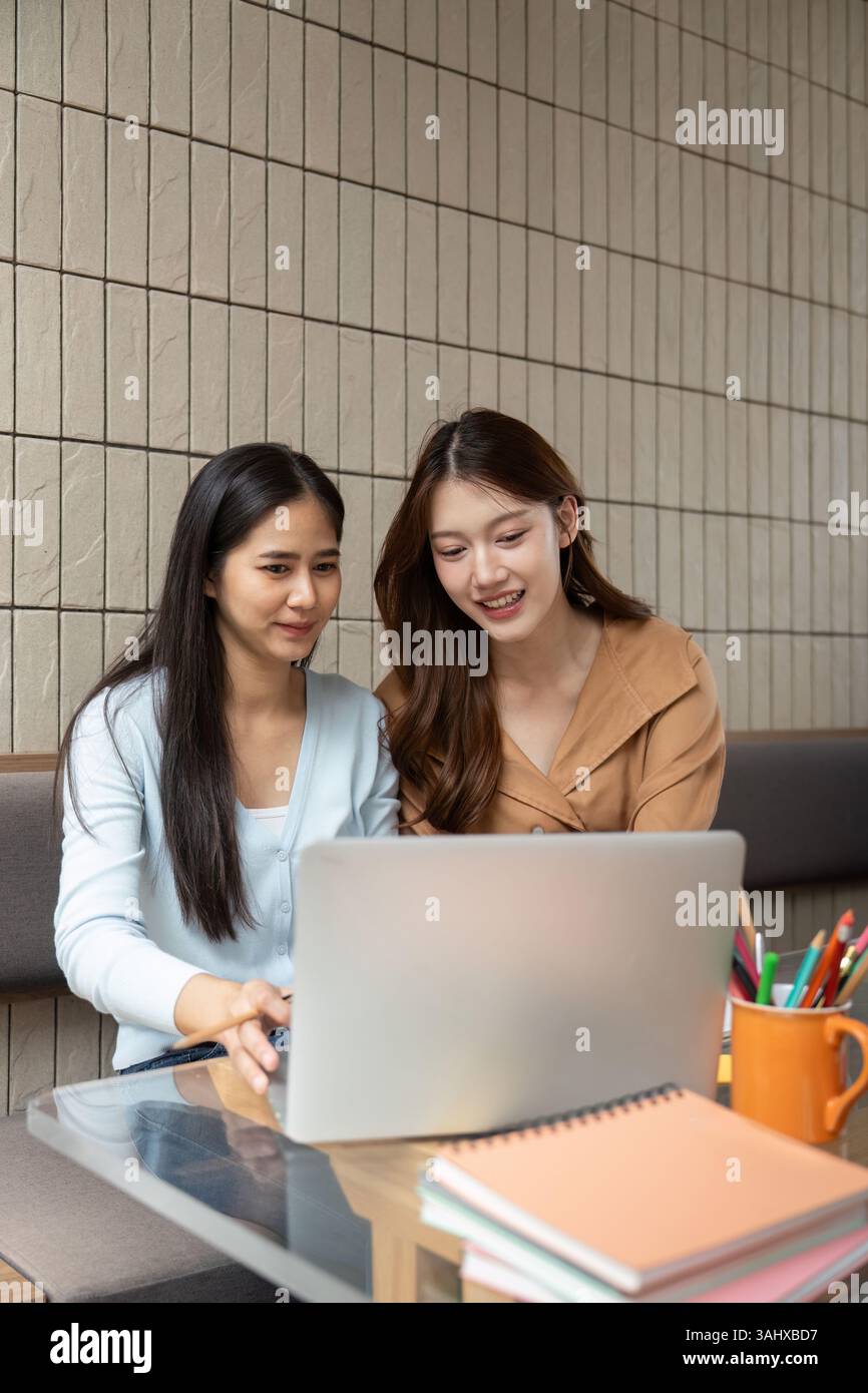 Study Session and Collaboration. Two university students engaged in a collaborative study session at a cafe. Stock Photo