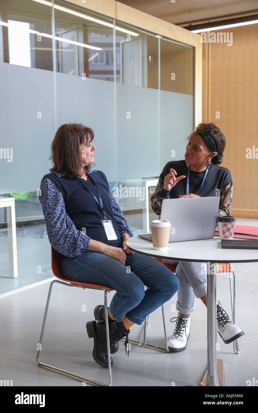 Coworkers using sign language in office Stock Photo