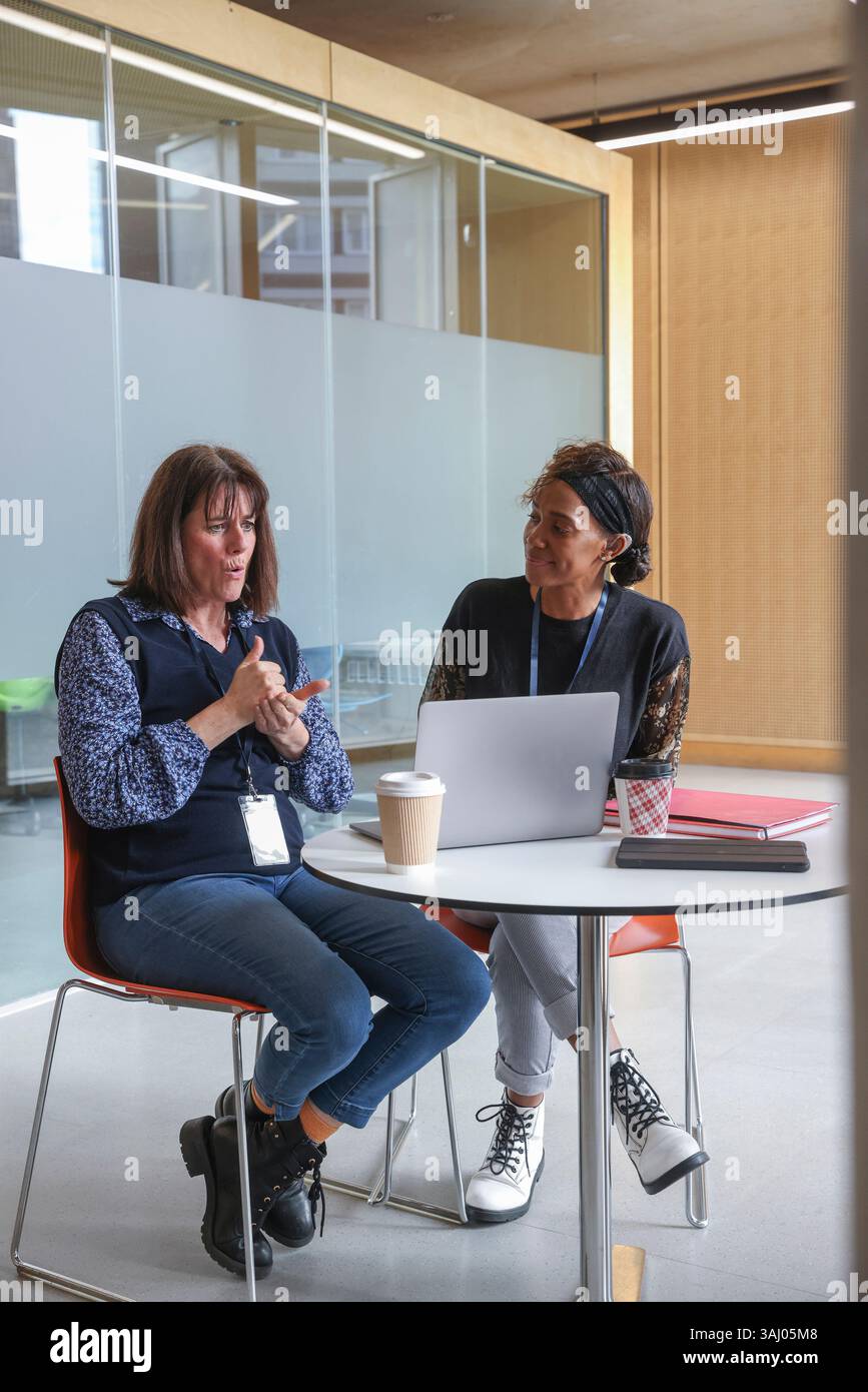 Coworkers using sign language in office Stock Photo
