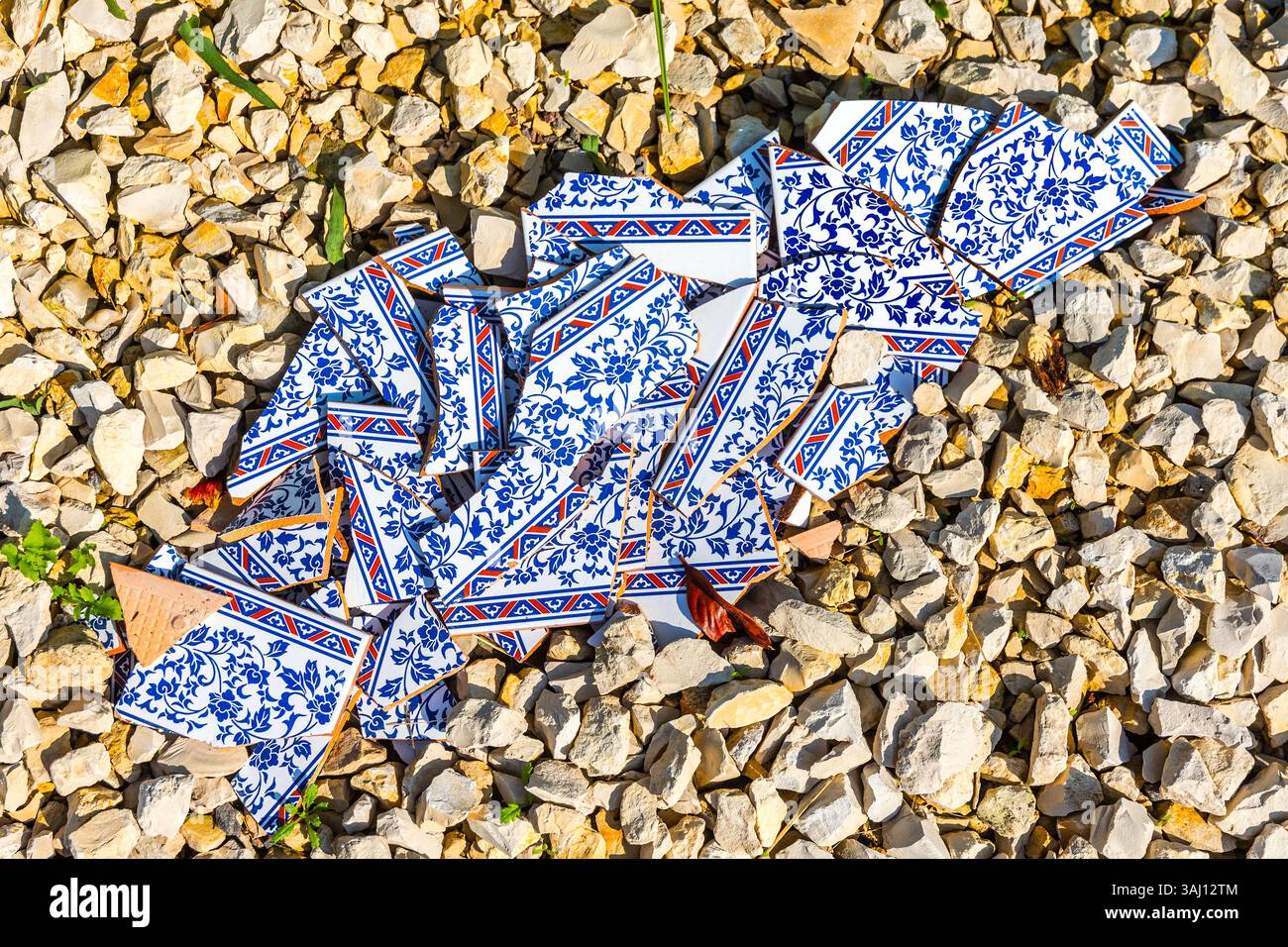 Broken ceramic tiles lying on gravel. Stock Photo