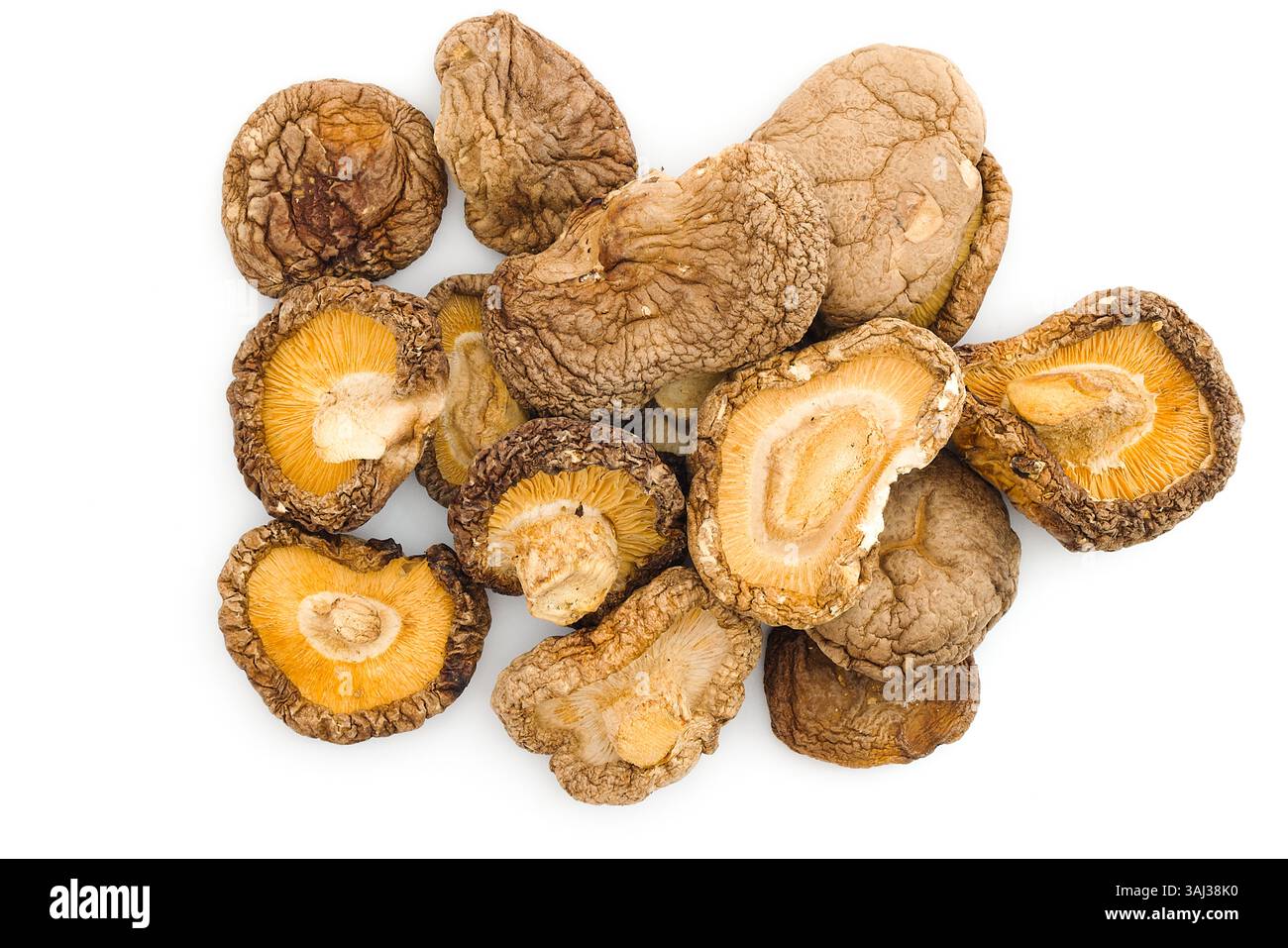 This photograph of dried shiitake mushrooms on white emphasizes their textured, rustic surfaces and rich umami tones, capturing the essence of a tradi Stock Photo