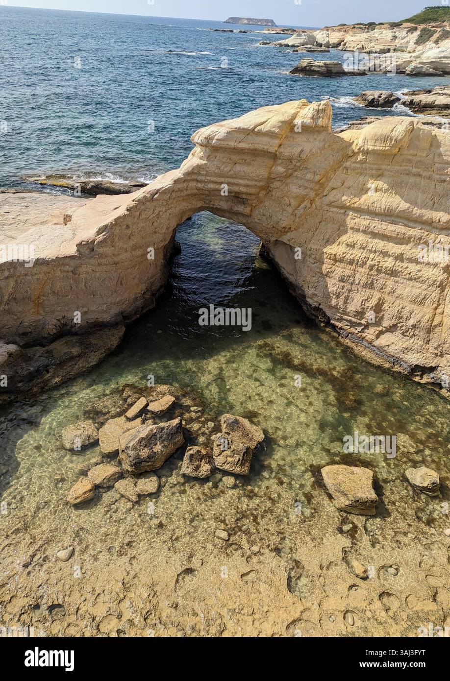 Julian’s Rock, Cyprus, a natural arch rising above crystal-clear shallows, shaped by time and kissed by the Mediterranean sun. - Smartphone Captured Stock Image Julian’s Rock, Cyprus, a natural arch rising above crystal-clear shallows, shaped by time and kissed by the Mediterranean sun. - Smartphone Captured Stock Image