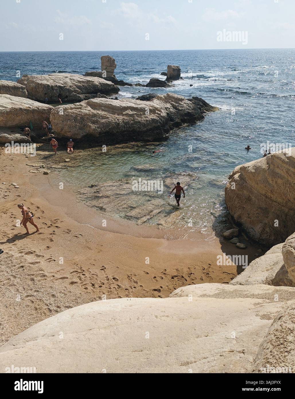 Ektoras Beach, Cyprus, a hidden cove where golden sand meets clear waters and rocky outcrops invite swimmers into the Mediterranean calm. - Smartphone Captured Stock Image Ektoras Beach, Cyprus, a hidden cove where golden sand meets clear waters and rocky outcrops invite swimmers into the Mediterranean calm. - Smartphone Captured Stock Image