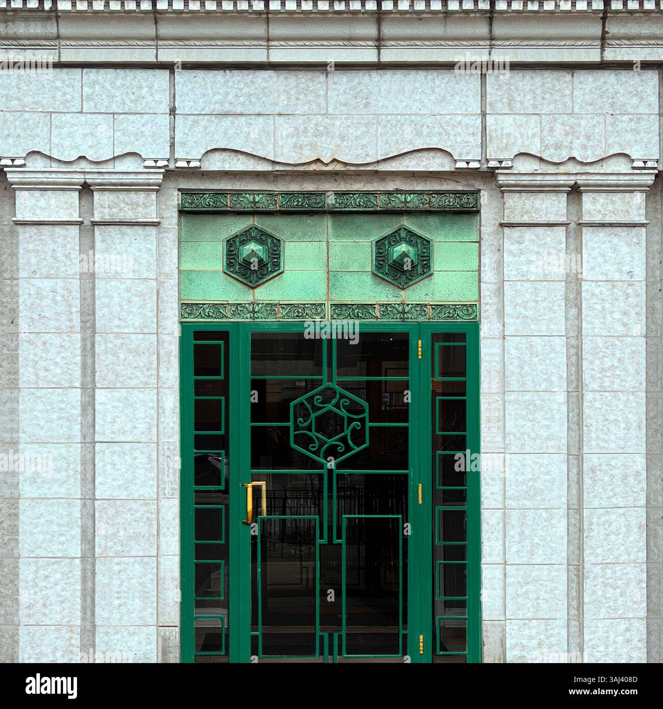 Art Deco green double doors with geometric ironwork and ornamental jade tiles, set in a white stone facade in Chicago. - Smartphone Captured Stock Image