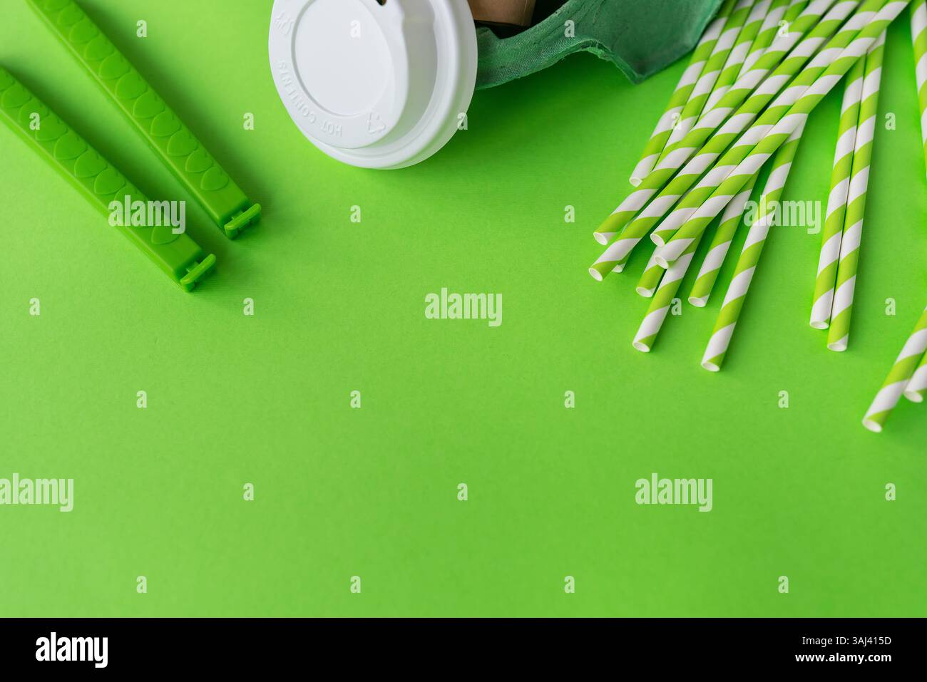 Eco-friendly disposable tableware and kitchenware on a green background. Stock Photo