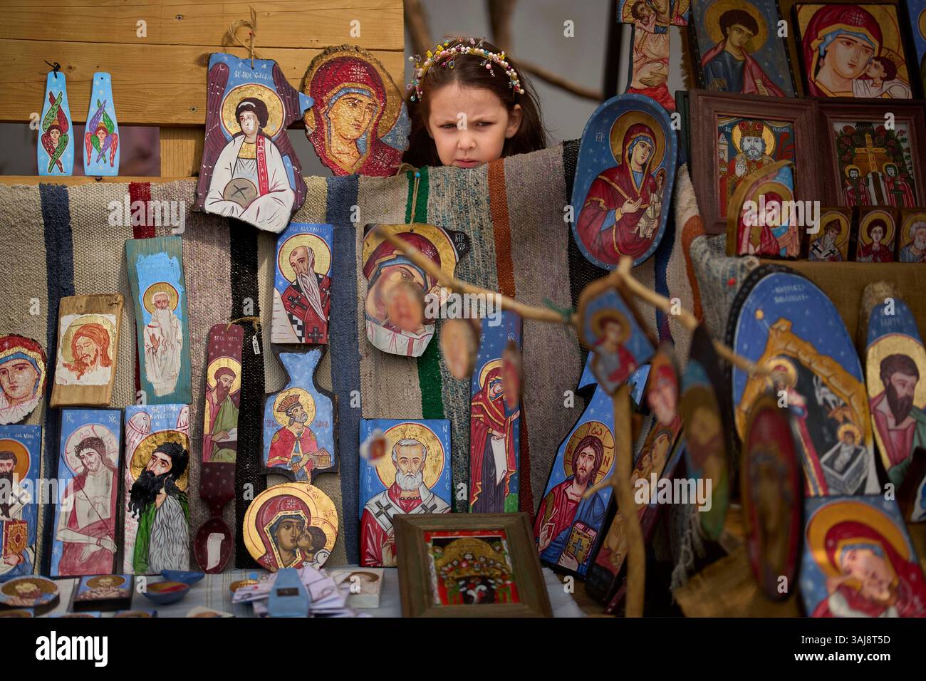 A child peers from behind a stand of an artist selling religious icons ...