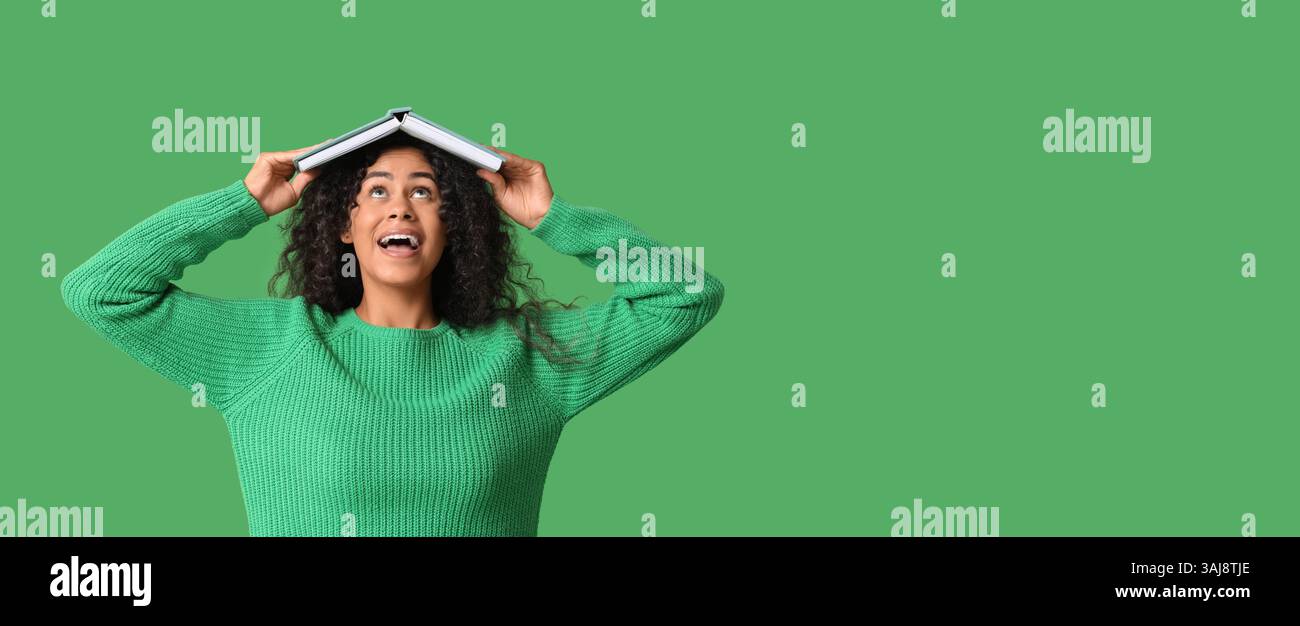 Happy young African-American woman with open book on her head against ...