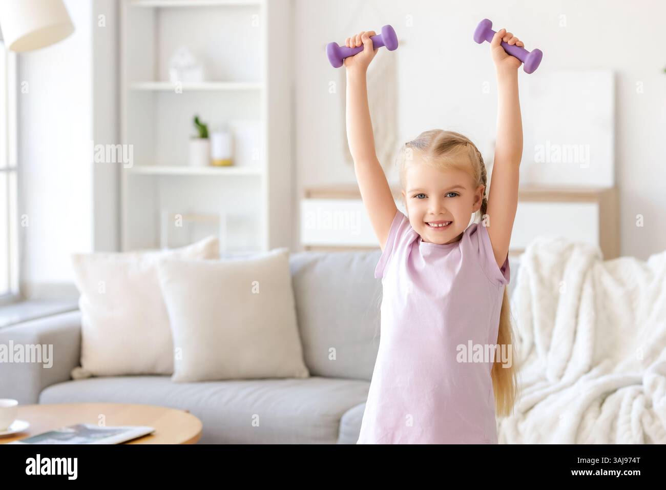Sporty little girl with dumbbells training at home Stock Photo - Alamy