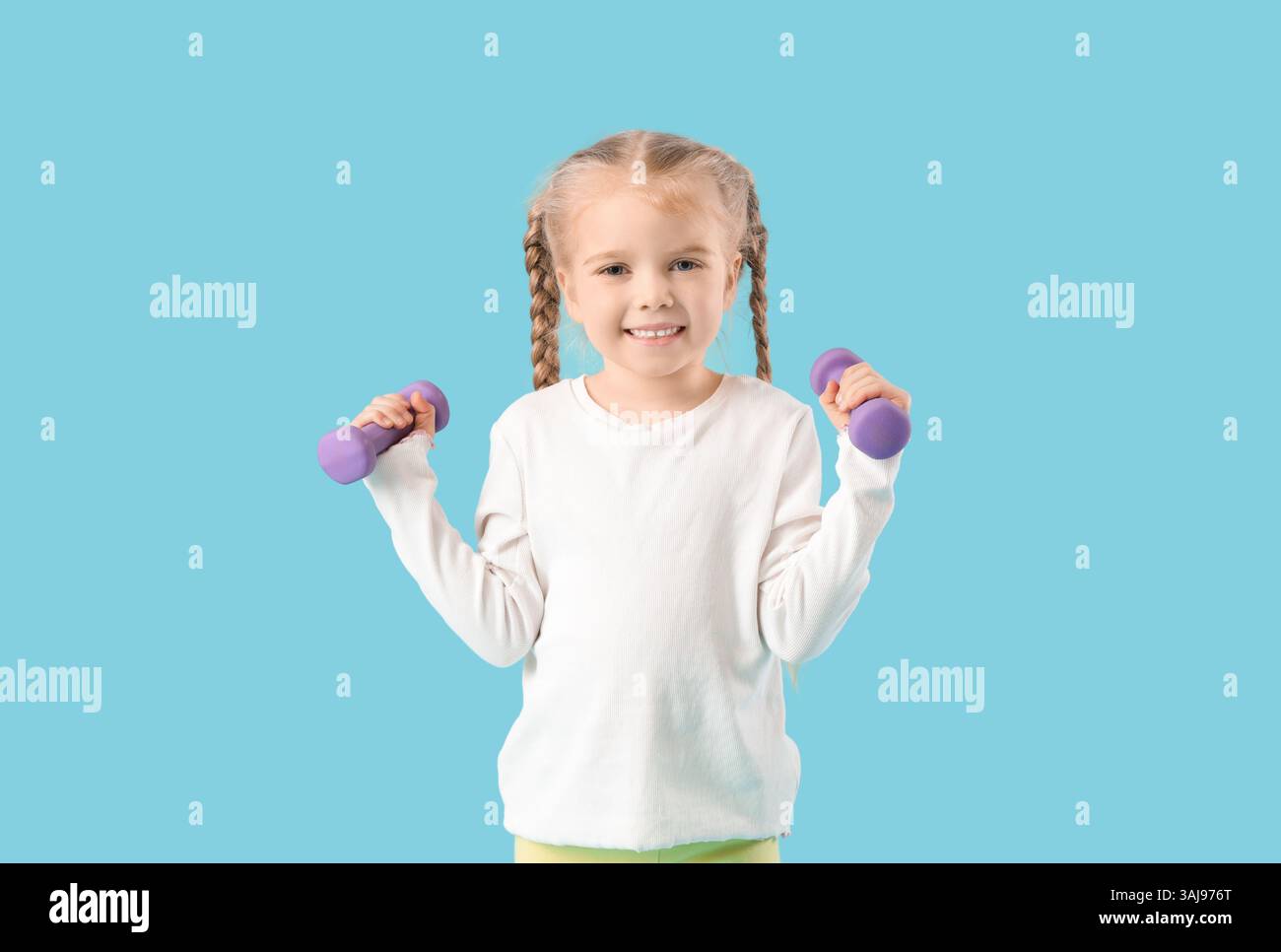 Sporty little girl with dumbbells on blue background Stock Photo - Alamy