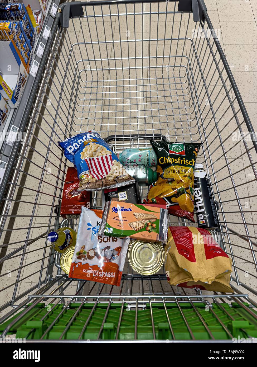 Metal shopping cart filled with various snacks and drinks, offering a ...
