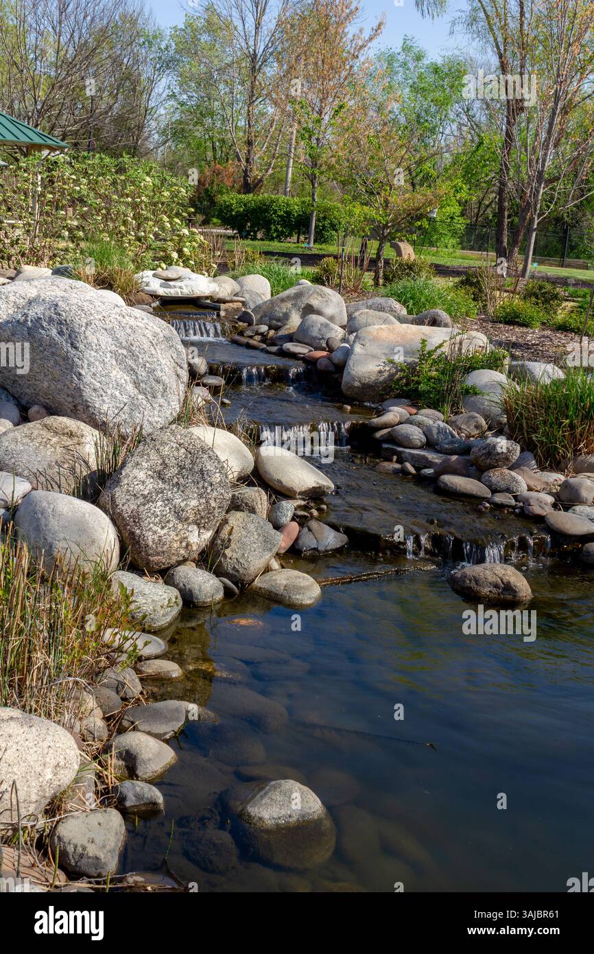 Small Spring Flowing From Rocks Small waterfall flowing through a landscaped rock garden stream ...