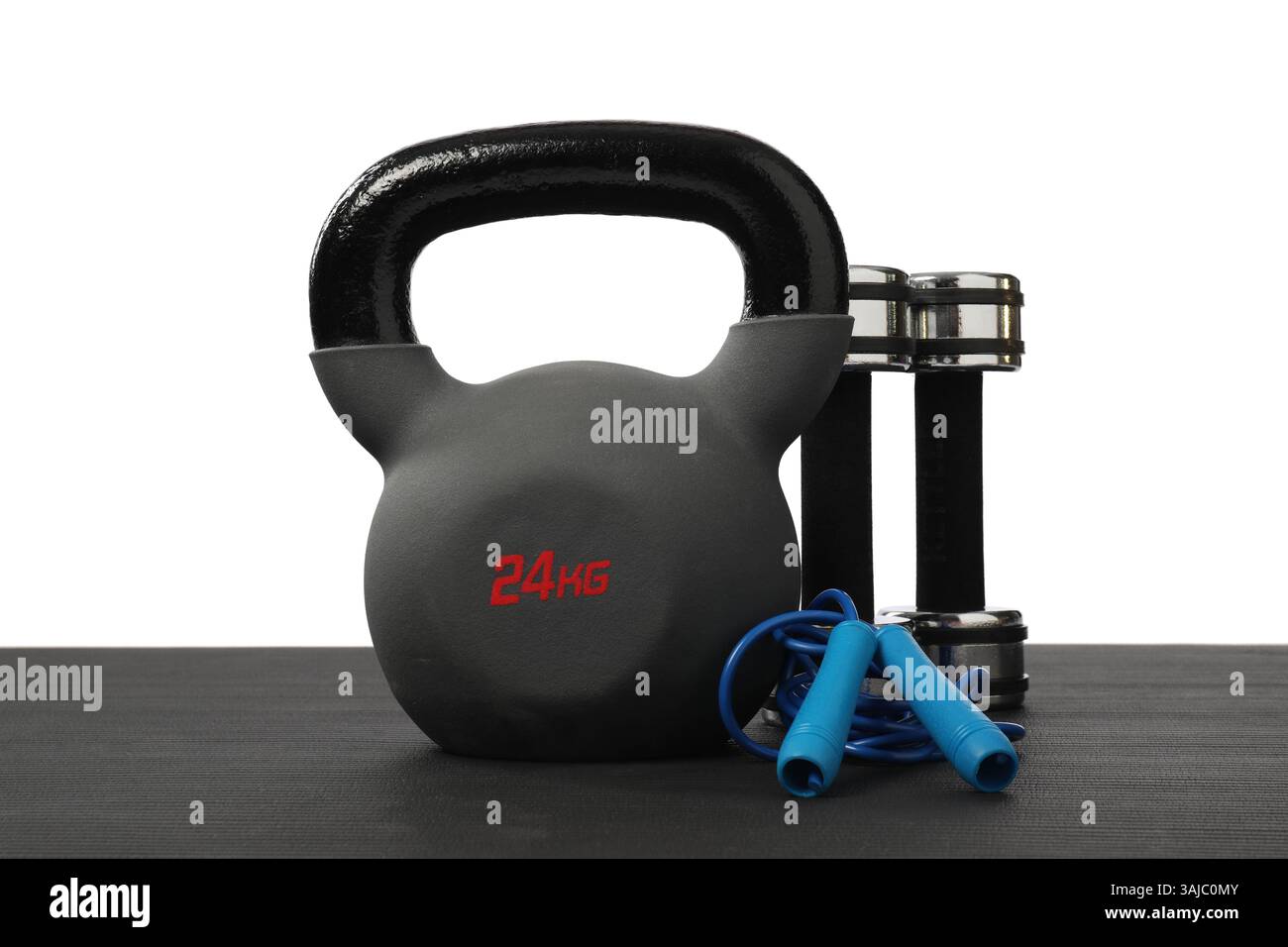 Kettlebell, jumping rope and dumbbells on fitness mat against white ...