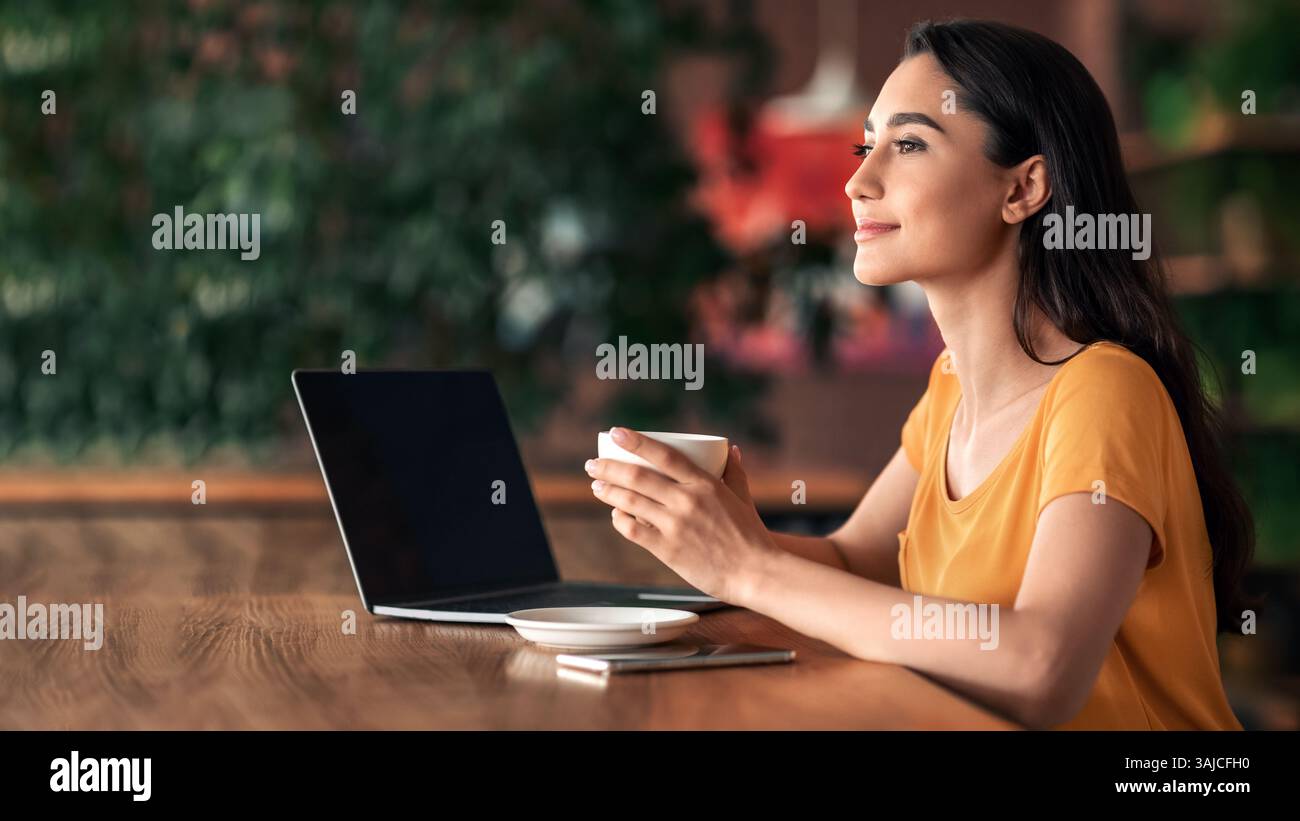 Happy young lady using laptop at cafe Stock Photo
