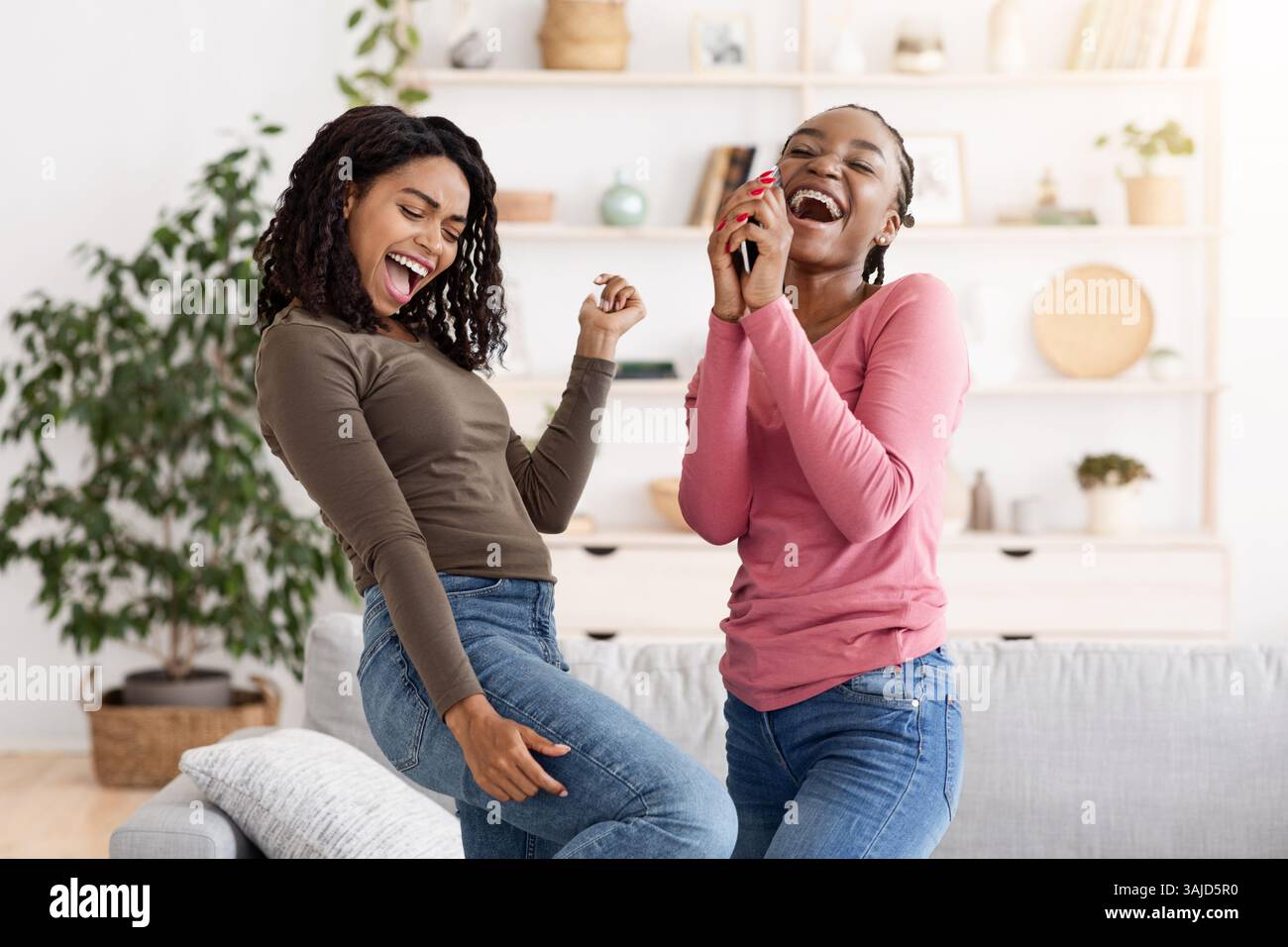 Carefree african american girlfriends singing and dancing at home Stock ...