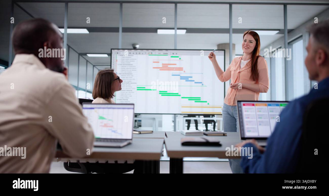 Multicultural Team Using Agile Gantt Schedule On Office TV Screen Stock Photo