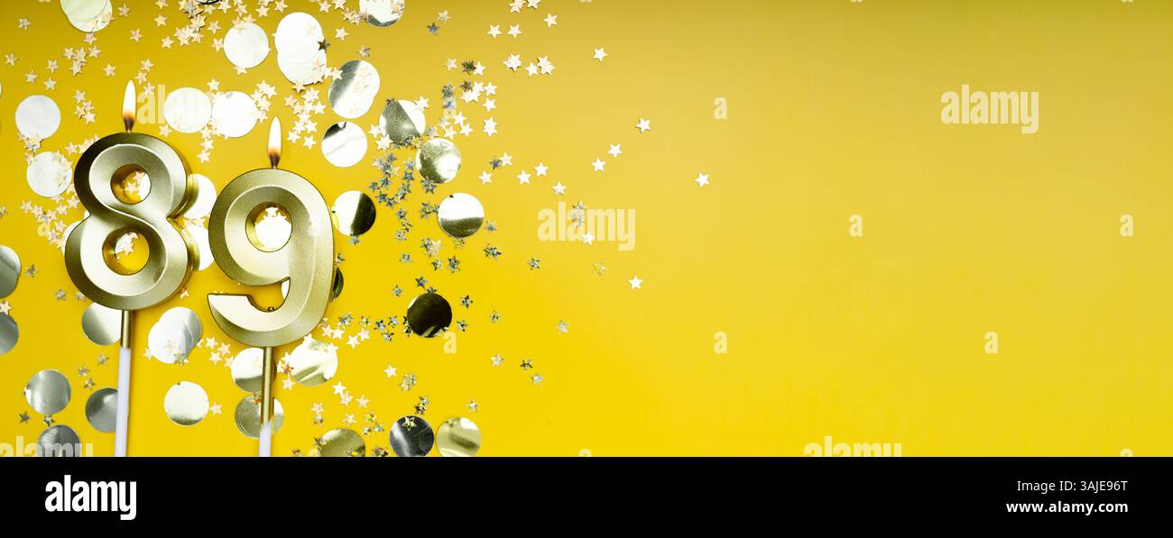 Eighty-nine years birthday. Number 89 golden celebration candle. Yellow festive background. Concept of celebrating birthday or anniversary. Banner. Stock Photo
