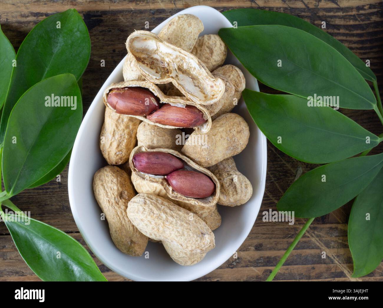 Peanuts in shell on a table with peanut leaves Stock Photo