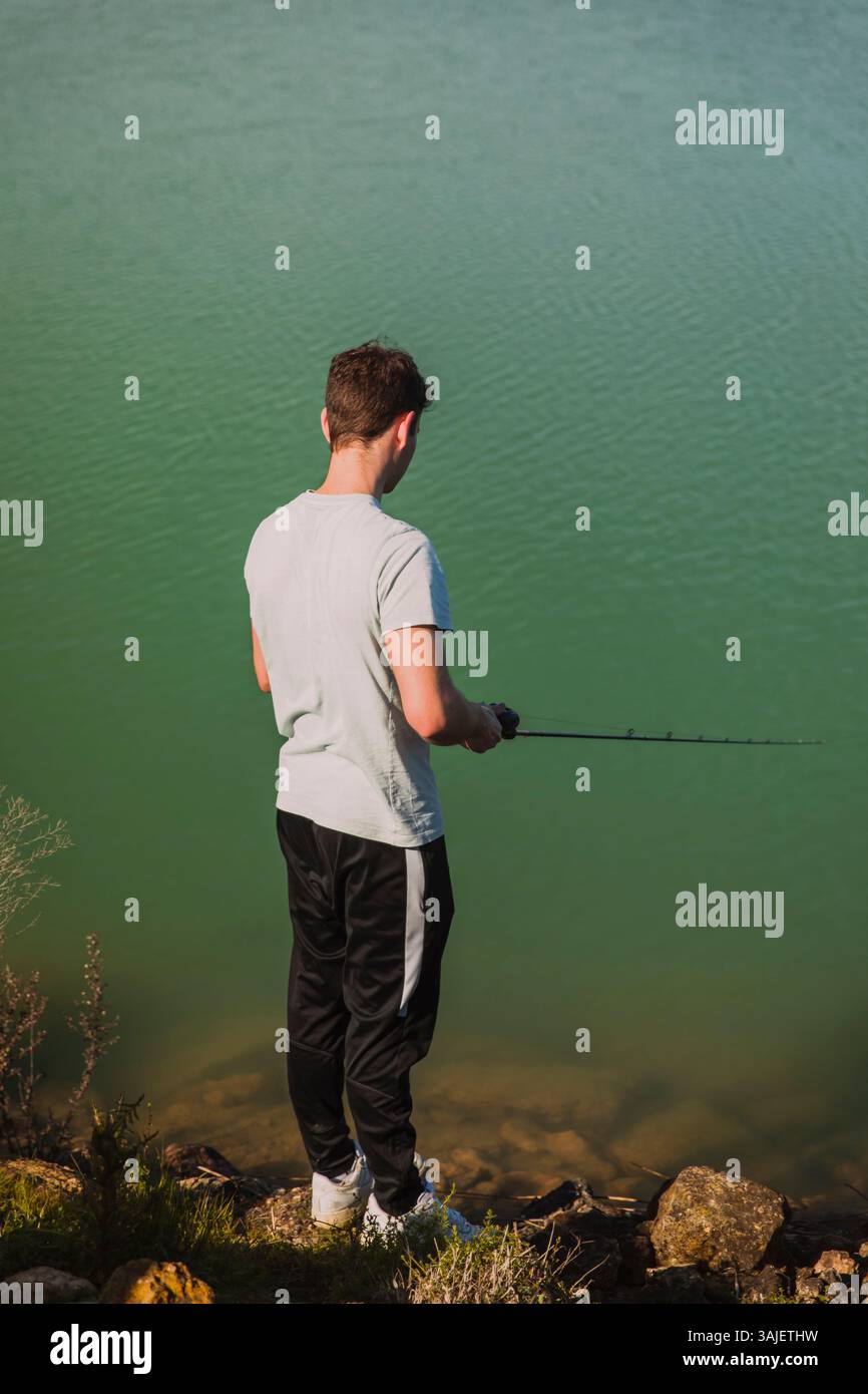 Man Fishing by Lake Shore Seen from Behind Stock Photo - Alamy