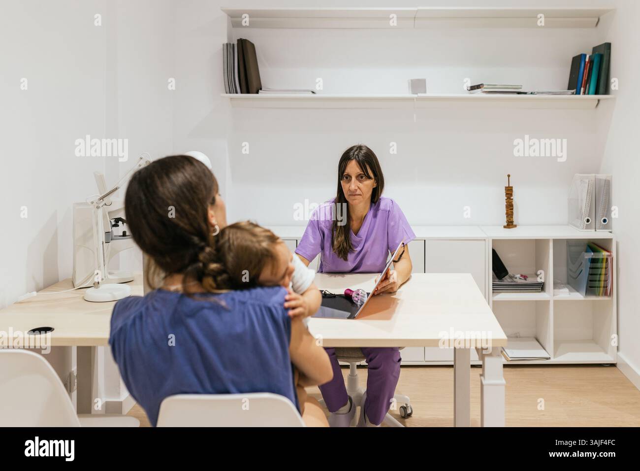 Optometrist talking with mother holding her baby daughter Stock Photo