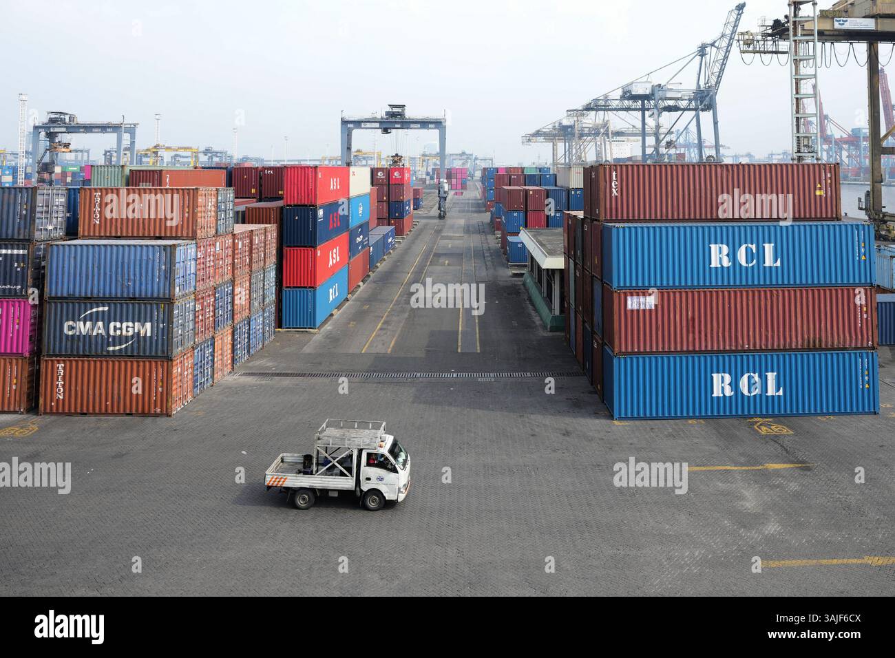 A pick up truck drives past shipping containers stacked at Jakarta ...
