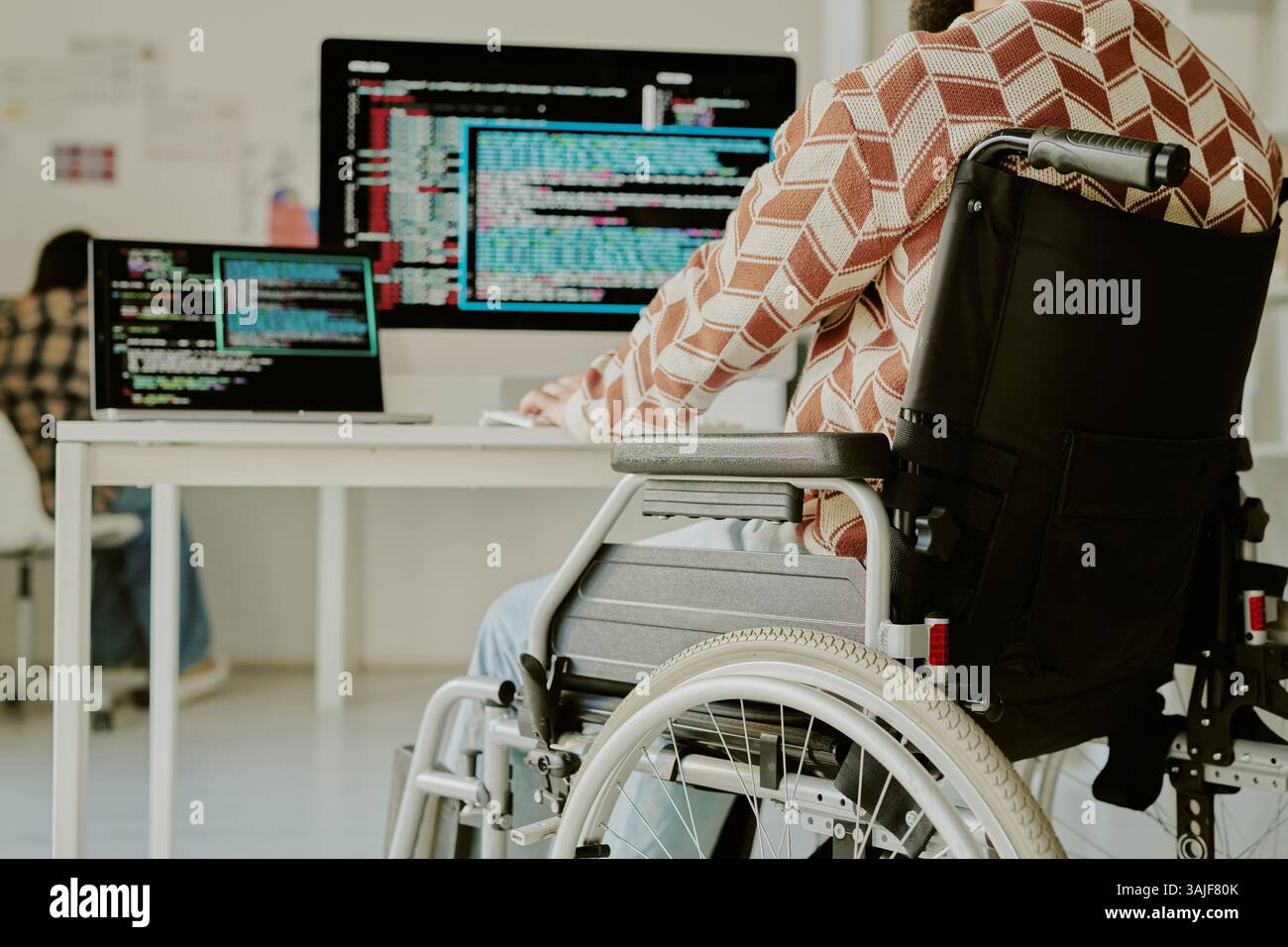 Low angle shot of unrecognizable programmer with disability coding on computer at work desk in spacious office Stock Photo