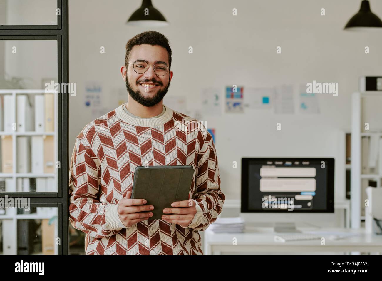 Waist up portrait of handsome young adult programmer with black tablet smiling widely for photo Stock Photo
