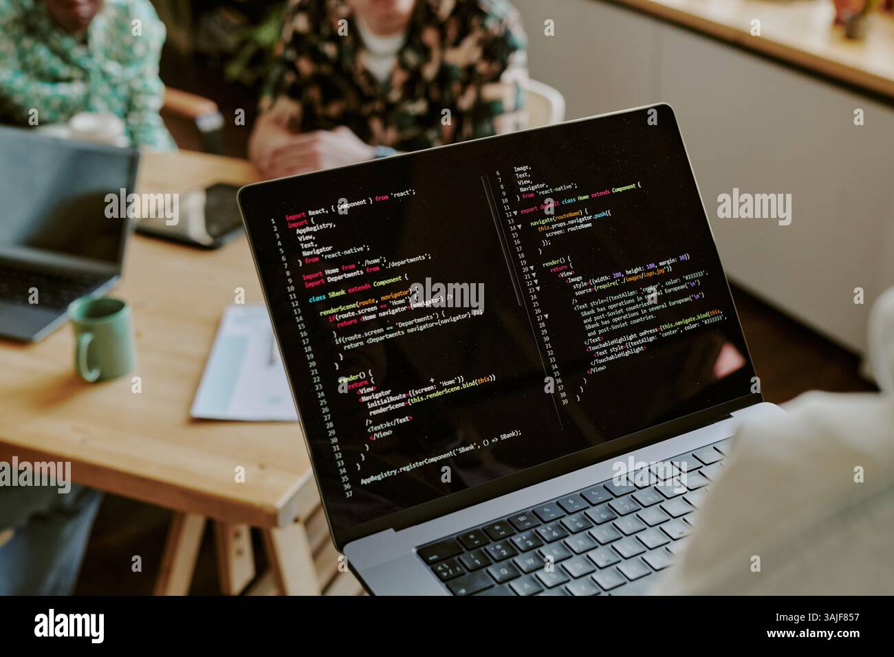 Over shoulder view of silver laptop with black screen full of code ...