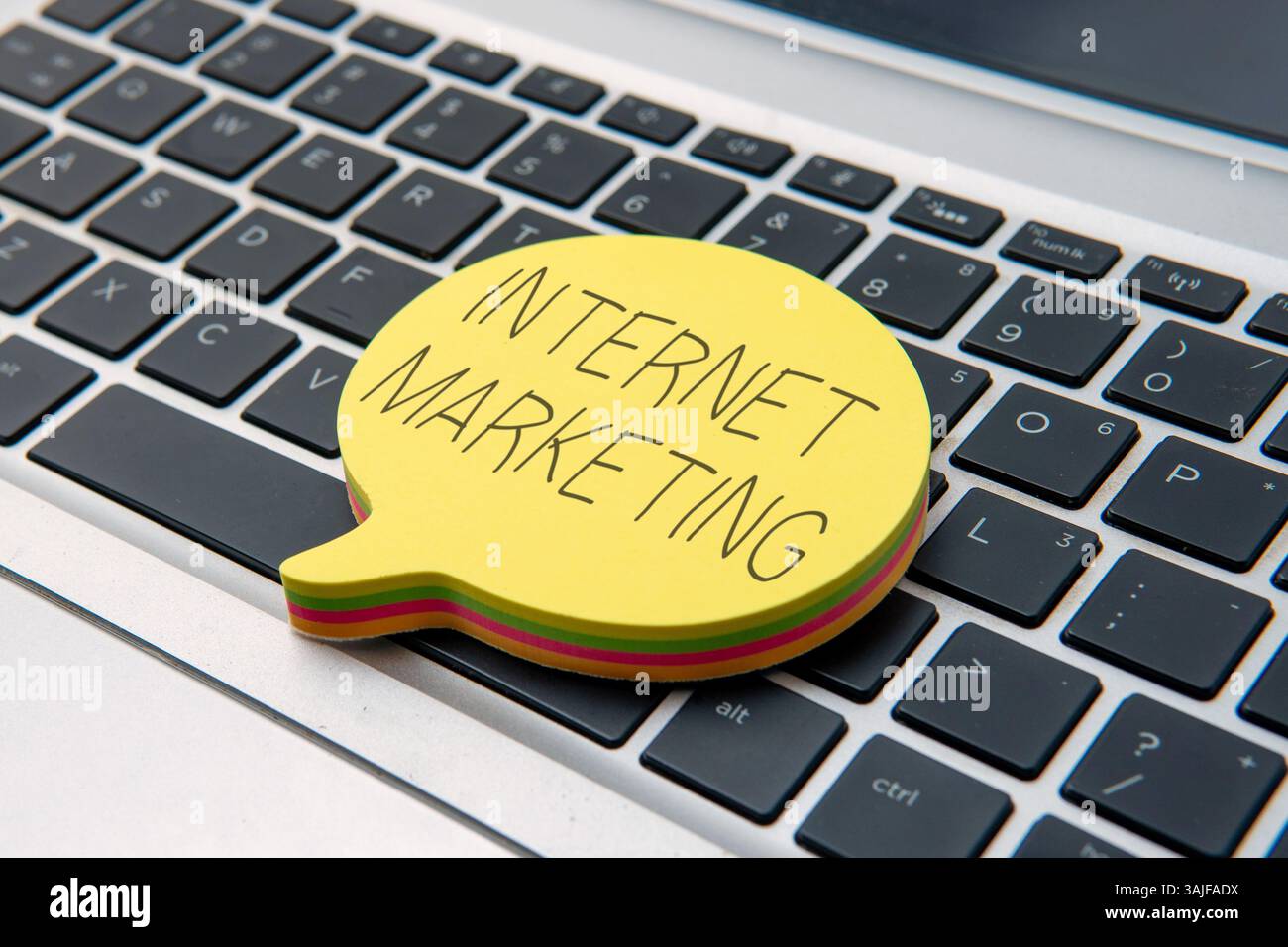 Yellow speech bubble on top of laptop keyboard with text INTERNET MARKETING. Business and technology concept. Stock Photo
