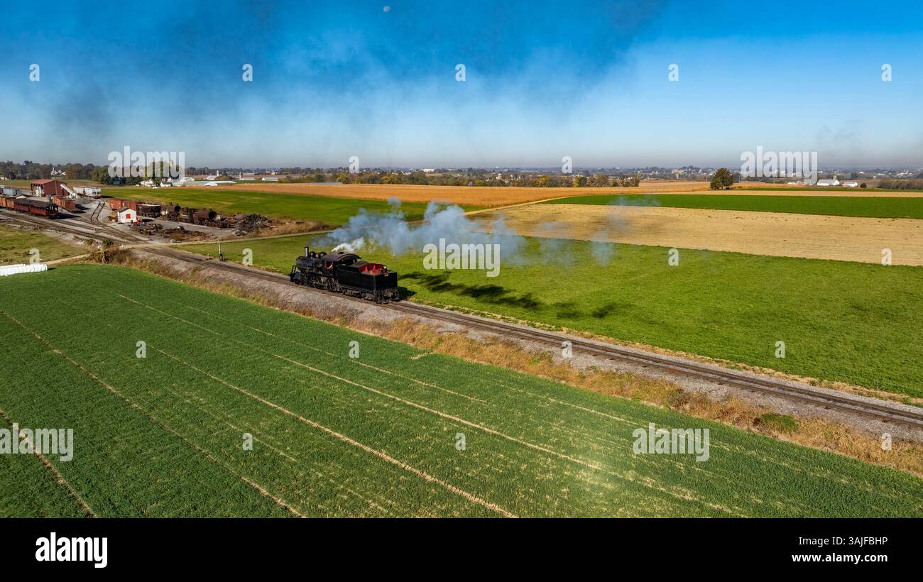 Puff Along A steam train puffs along a rural track, releasing clouds of smoke as ...