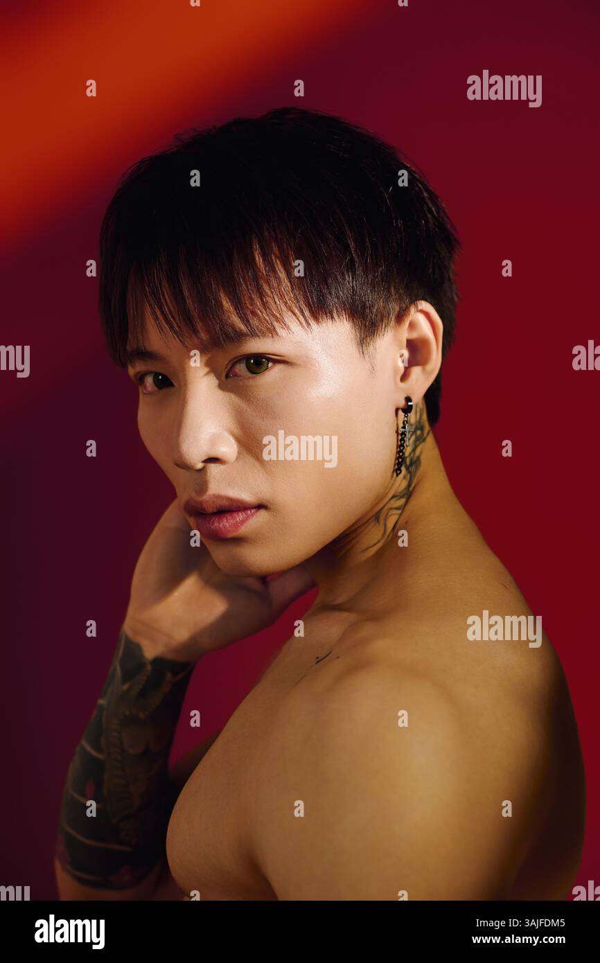 A stylish young man poses confidently against a bold red background ...
