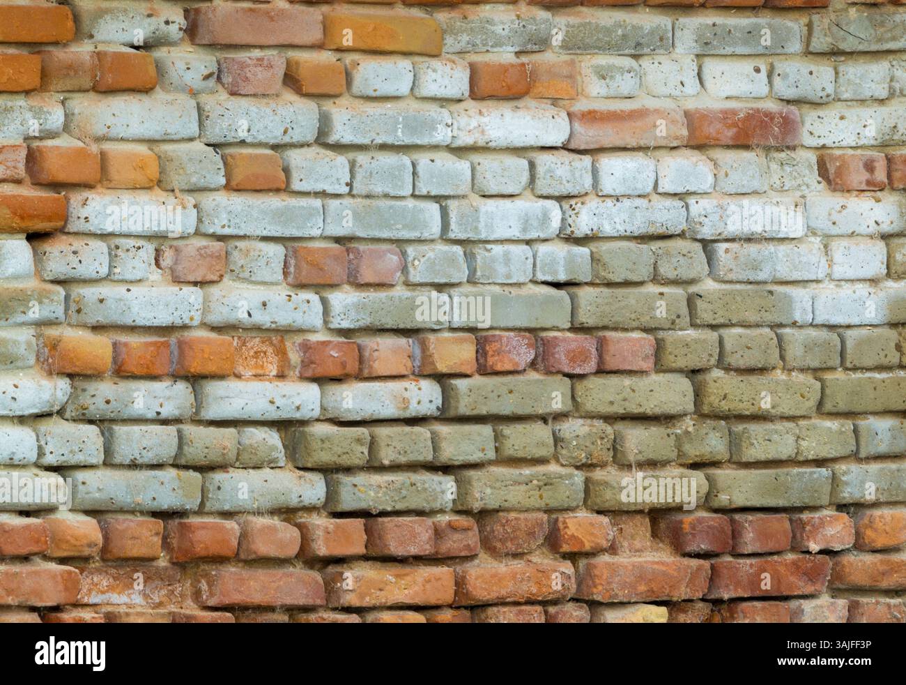 Rows of multi-coloured and weathered old bricks with rounded edges - Stock Image