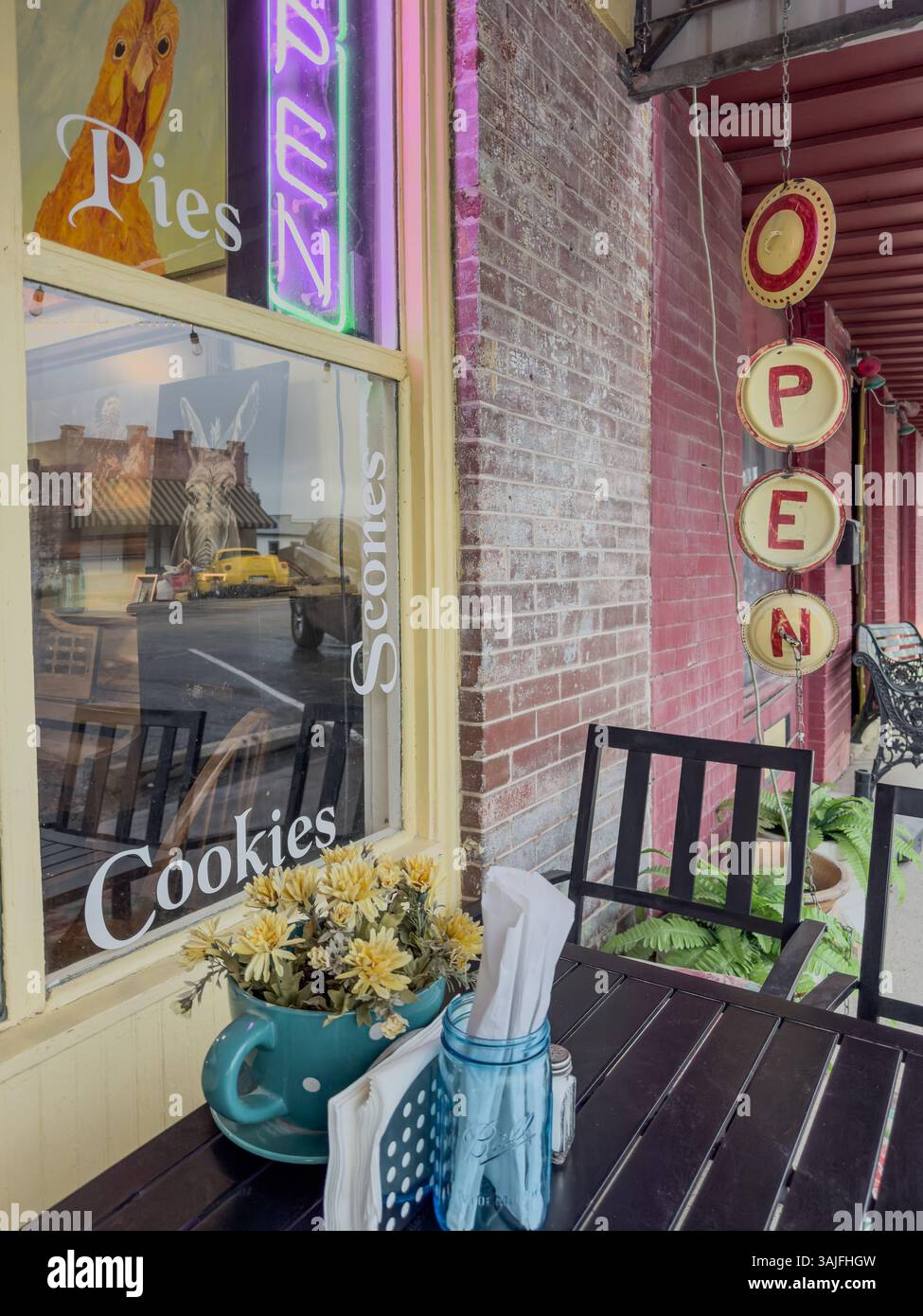 Closeup of al fresco dining in the front of Olde World Bakery & Cafe, an open sign, Smithville, Bastrop County, Texas, USA. - Smartphone Captured Stock Image
