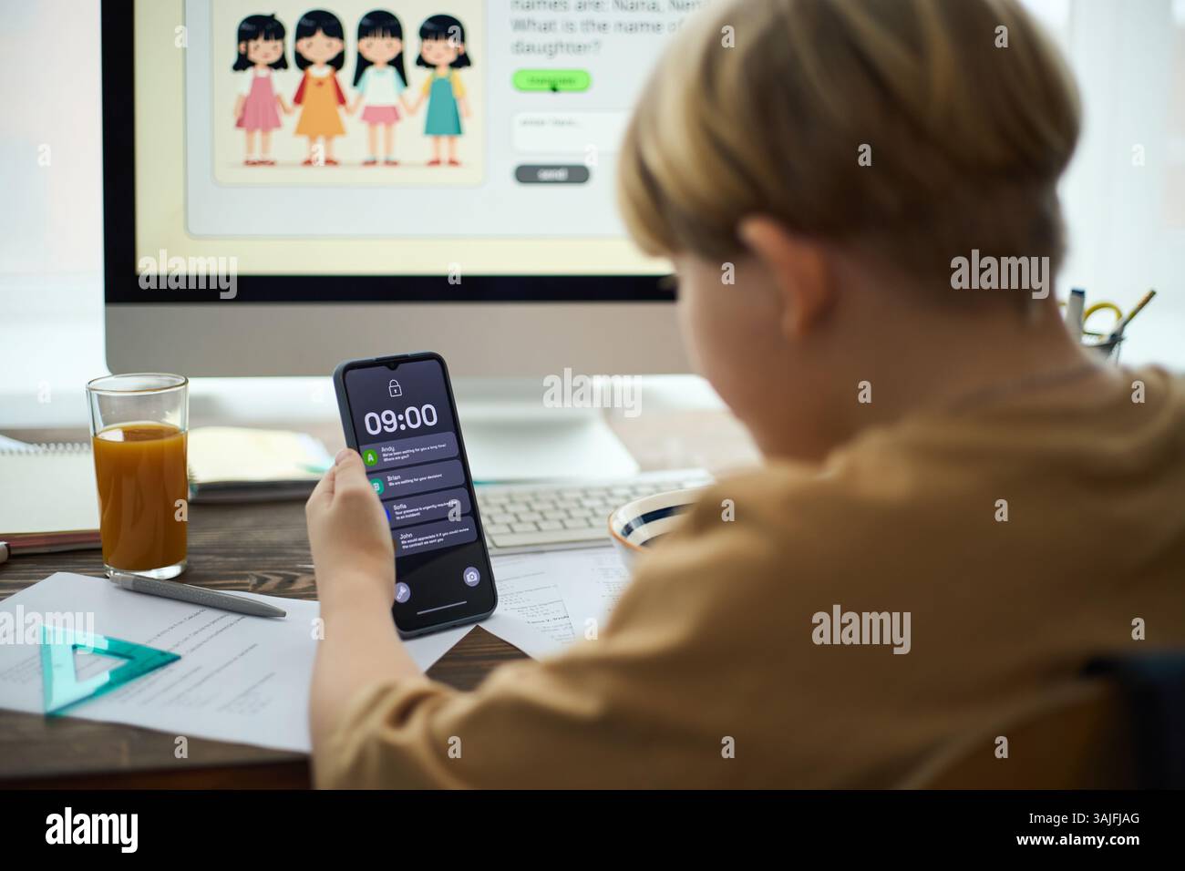 Boy checking time on smartphone while doing school homework, with ...