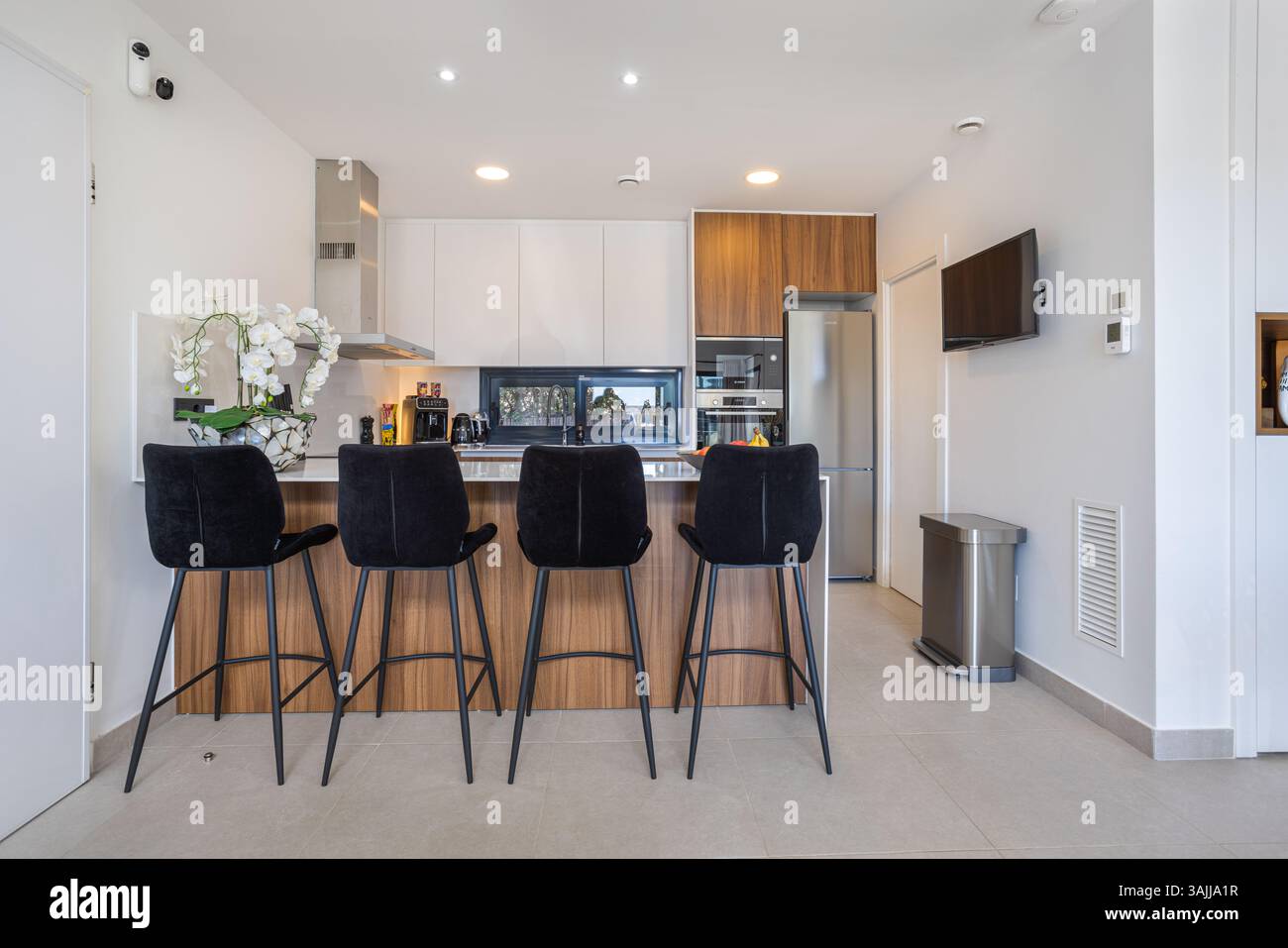 Modern kitchen interior with a sleek island and four black velvet bar ...