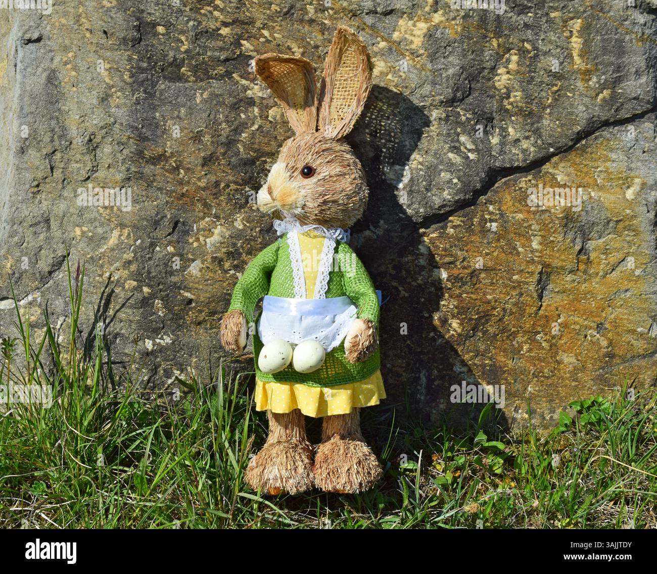 Easter bunny in the grass in front of a large ston Stock Photo
