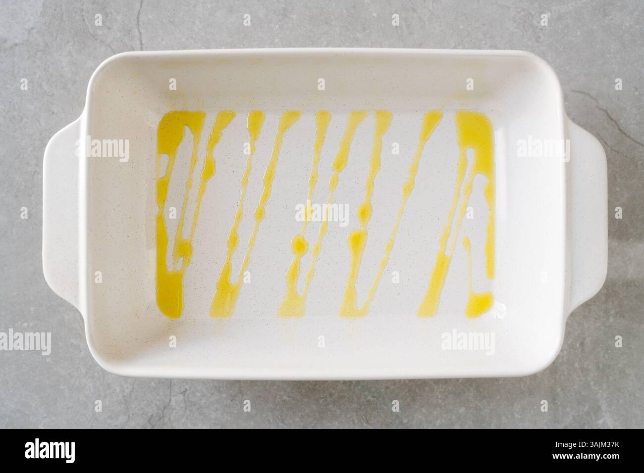 White rectangular baking dish with olive oil drizzled in vertical lines. Stock Photo