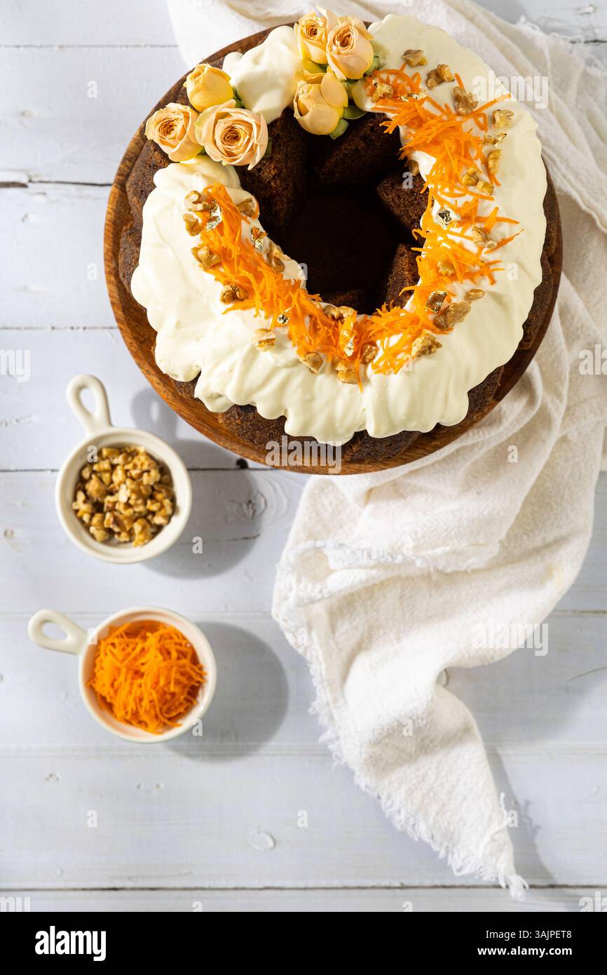 Carrot Cake with Cream Cheese Frosting and Fresh Flowers – White Wooden Background Stock Photo