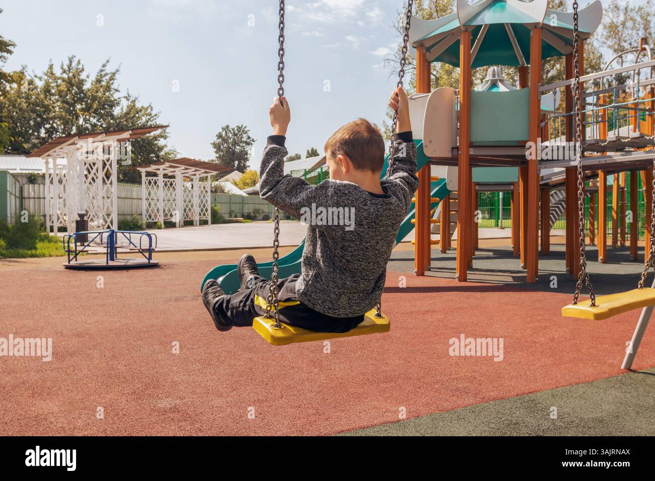 Kids Using Playground Rings Smiling boy hanging from exercise rings in outdoor playground. Autumn ...