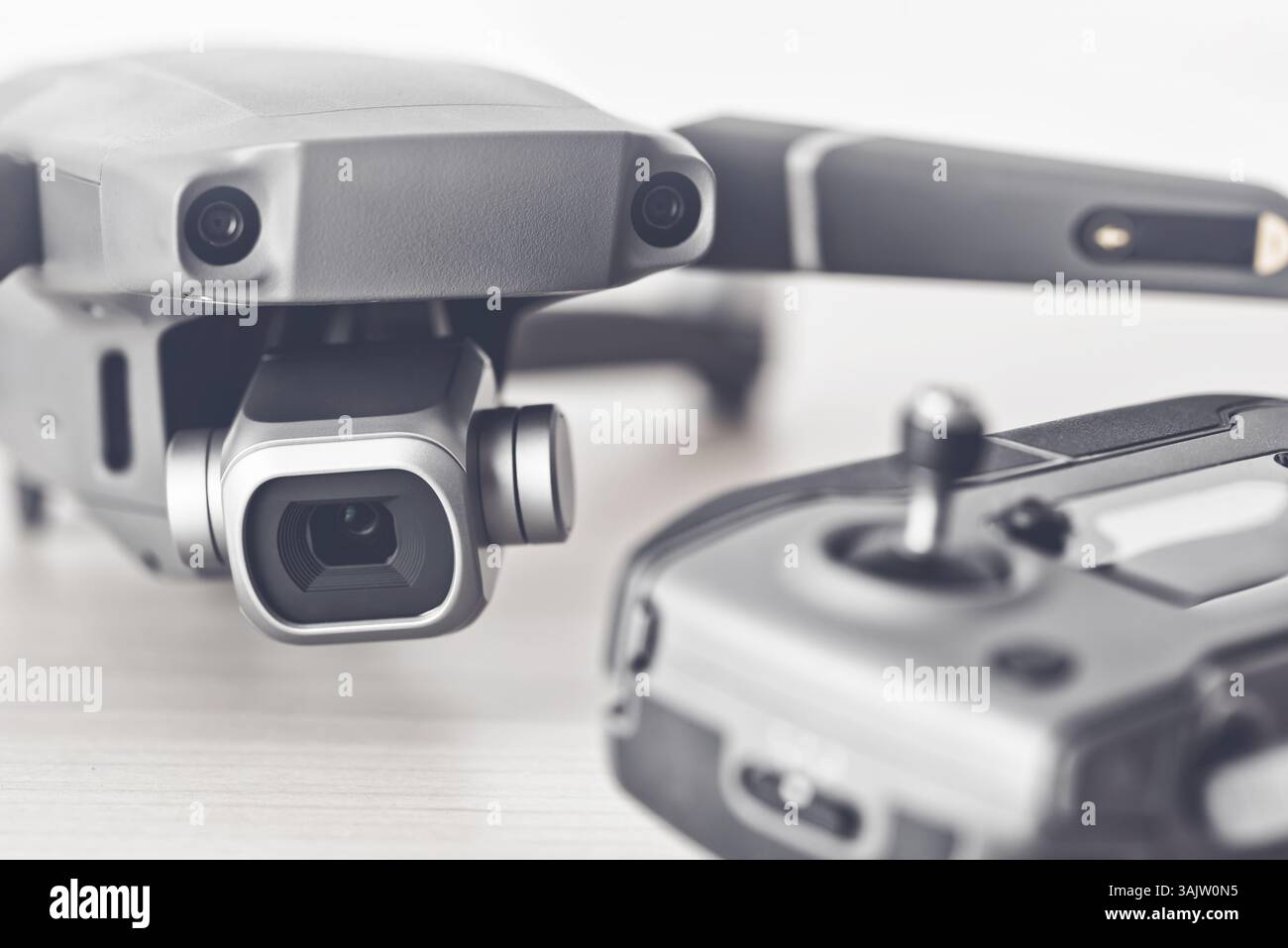 Gray quadcopter drone resting alongside remote control, revealing professional aerial imaging equipment for photography and video production Stock Photo