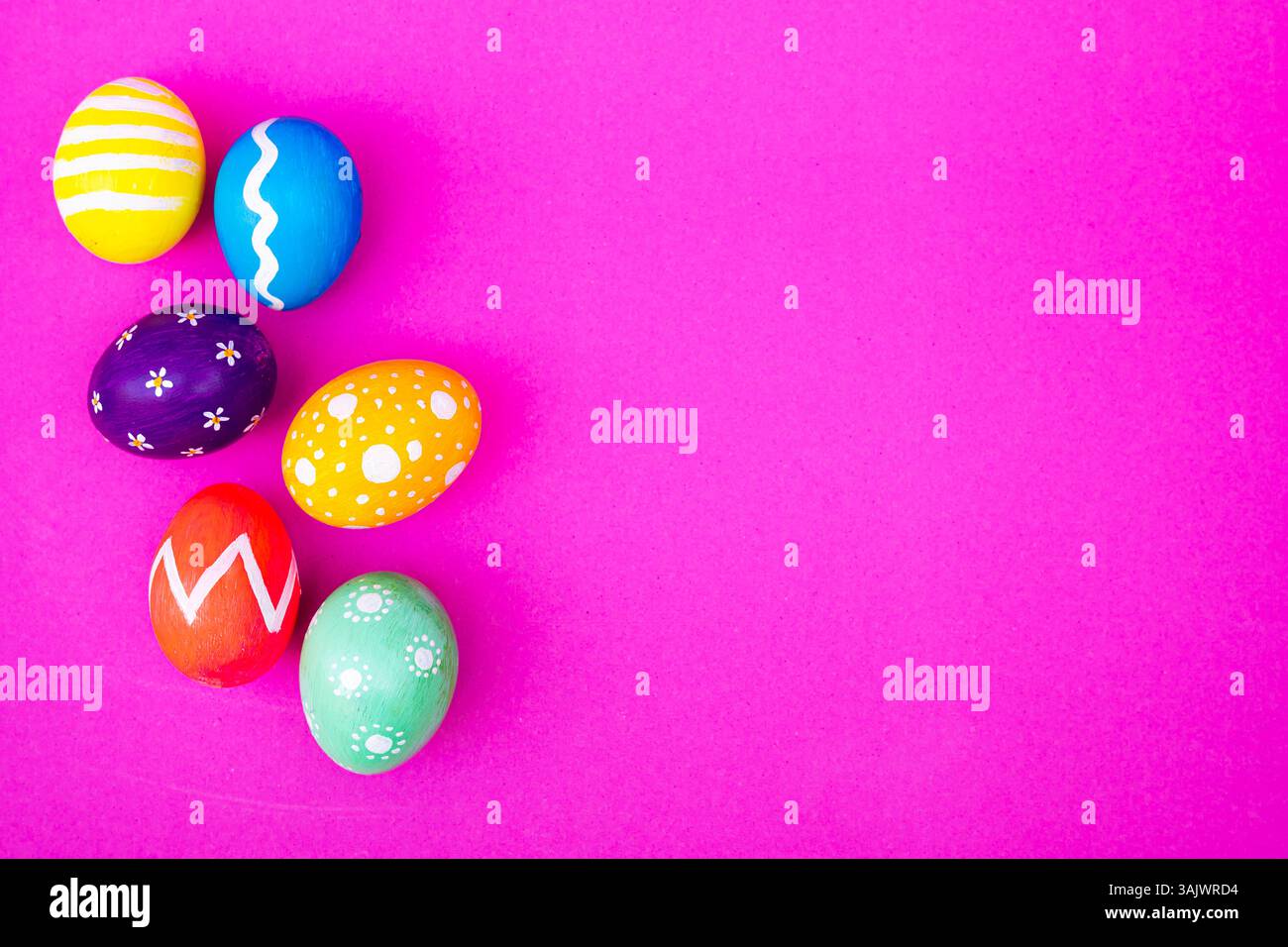 A top view of colorful eggs, offering a spring holiday vibe with a soft light pink setting. Stock Photo