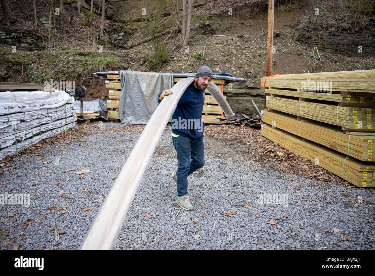 Tom McQuillan, a delivery driver for Hodgkiss Lumber, carries decking ...