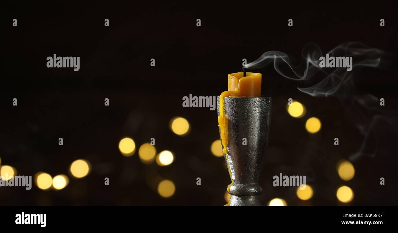 Extinguished Lights Extinguished candle in candlestick against dark background with blurred ...