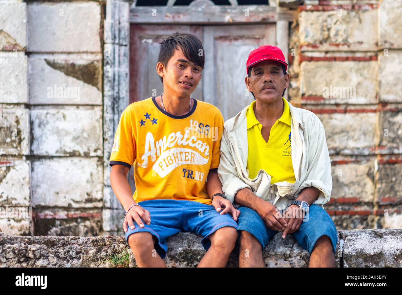 Two local male guides posing in front of the ruins of the Isla Gigantes Lighthouse, a Spanish colonial-era structure in Iloilo, Philippines Stock Photo