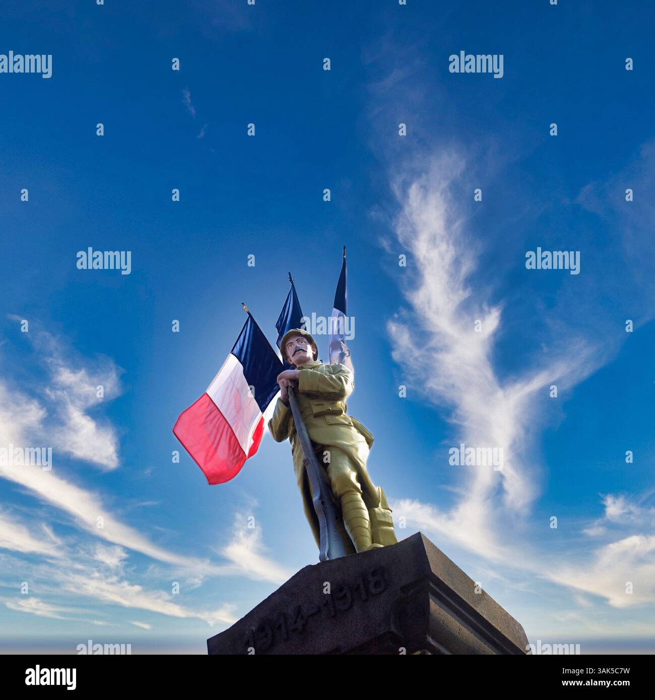 War monument honoring soldiers in Auvergne, with French flags under a ...