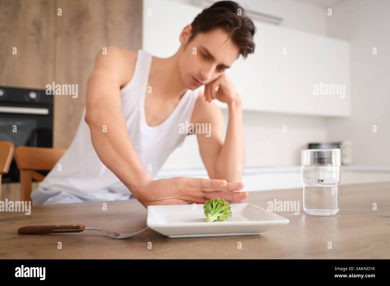 Young man with anorexia refusing from food in kitchen Stock Photo