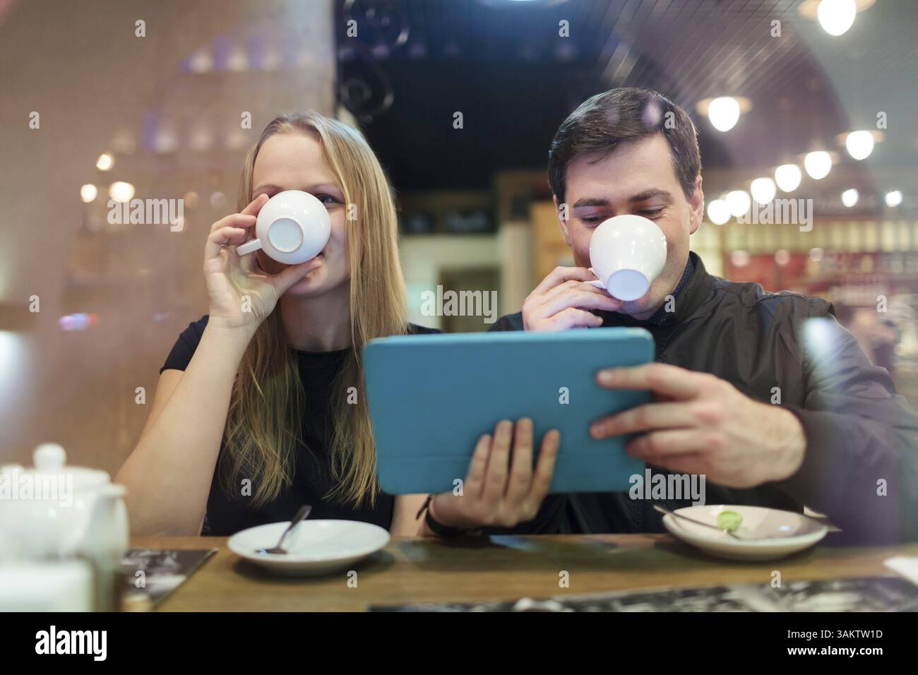 Man and woman drinking coffee while holding a smart tablet Stock Photo